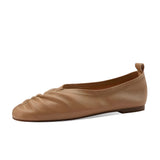 Beige women's soft leather ballet flats, flexible slip-on shoes with a simple and elegant design, displayed on a wooden surface.
