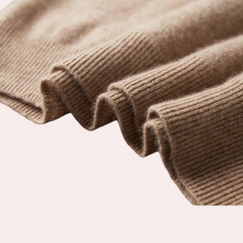 Beige wool cowl neck sweater with long sleeves displayed on a wooden background, showcasing its elegant design and cozy fabric.