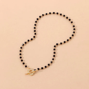 Black bead choker necklace with a gold bird pendant, featuring minimalist nature-inspired jewelry design.