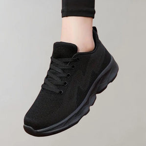 Black breathable sneakers designed for both running and walking, featuring a lightweight construction with synthetic rubber soles, shown worn on a human foot.