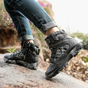 Black camo tactical waterproof hiking boots being worn outdoors on grass, showcasing rugged design and high-traction soles, with a cool grey color scheme.