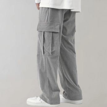 Black corduroy cargo pants made of durable cotton with a soft drawstring, featuring multiple pockets and a relaxed fit around the waist and knees.