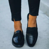 Black crocodile loafers for women, luxury designer slip-on shoes, paired with denim jeans.