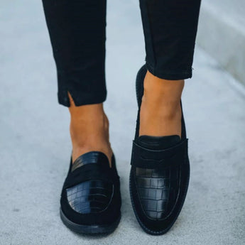 Black crocodile loafers for women, luxury designer slip-on shoes, paired with denim jeans.