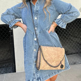 Black denim dress paired with a fringe purse and Western ankle boots, featuring a stylish ensemble perfect for a trendy, casual look.