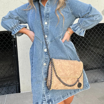 Black denim dress paired with a fringe purse and Western ankle boots, featuring a stylish ensemble perfect for a trendy, casual look.
