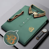 Black designer polo shirt with plaid collar and gold crest logo displayed.