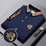 Black designer polo shirt with plaid collar and gold crest, featuring short sleeves and stylish design.