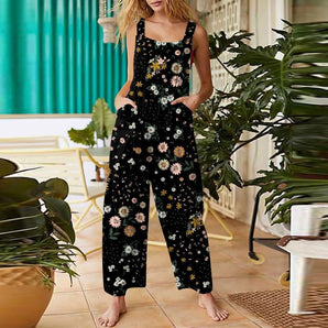 
A woman wearing a black floral sleeveless jumpsuit, showcasing a casual summer style with pockets, standing and emphasizing the shoulder, waist, and thigh areas.