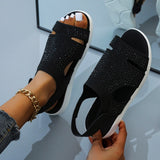 Black glitter rhinestone sandals being held by a hand, showcasing the trendy and comfortable flat design with a focus on the sparkling embellishments.