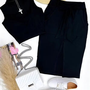 Black high-waisted skirt paired with women's white sneakers, featuring a trendy and casual summer look.
