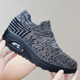 Black knit slip-on sneakers designed for breathability and lightweight comfort, showcased against a sportswear-themed background.