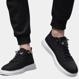 Black lace-up low-top sneakers for men with a sleek design, featuring white and grey accents, photographed on a clean background.