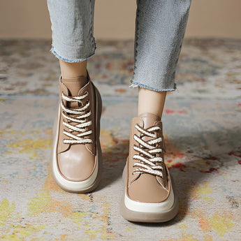 Black leather high-top sneakers with a thick sole, styled with denim jeans, capturing a trendy urban fashion look.