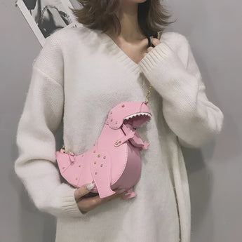 Black leather horse-shaped crossbody bag with a gold chain strap featured against a backdrop highlighting pink and dressed outerwear elements.