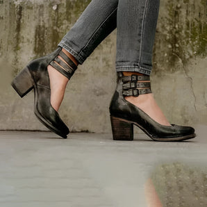 Black leather Mary Jane shoes with a chunky heel and an ankle strap, shown on a model wearing denim.