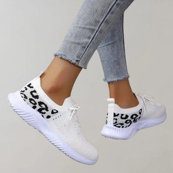 Black leopard print women's sneakers worn with denim jeans, showcasing a stylish and comfortable footwear design.