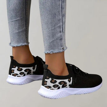 Black leopard print women's stylish comfortable sneakers displayed on a grey denim background.