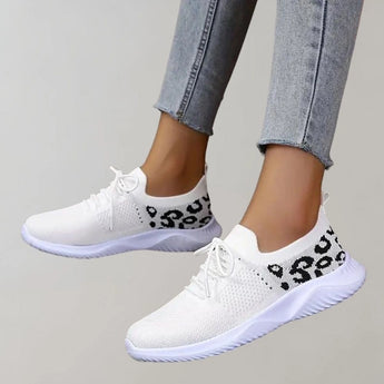 Black leopard print women's sneakers with a stylish and comfortable design, shown on a person wearing denim jeans.
