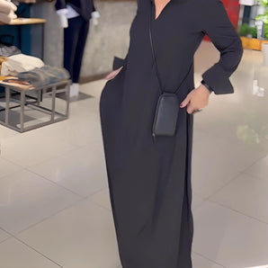 
A woman wearing a black long sleeve maxi dress with pockets, showcasing an elegant and versatile style suitable for formal events. The dress features a fitted waist and floor-length design, ideal for making a fashion statement.