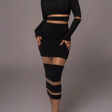 
A model wearing a black long sleeve sheer mesh midi cocktail dress that curves to highlight the waist and thighs. The dress features a fitted silhouette, with the hemline reaching just below the knees.