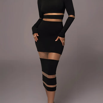 
A model wearing a black long sleeve sheer mesh midi cocktail dress that curves to highlight the waist and thighs. The dress features a fitted silhouette, with the hemline reaching just below the knees.