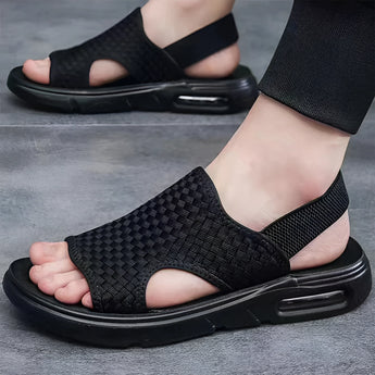 Black mesh breathable slippers with ergonomic sole, showcasing a stylish design in black and white tones. The slippers are designed to provide comfort with a focus on foot support and breathability.