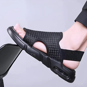 Black mesh breathable slippers with ergonomic sole being held in a hand, showcasing the front and side views.