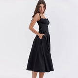 
A black midi dress with spaghetti straps, featuring an A-line silhouette suitable for evening and cocktail occasions. The dress is worn by a person, highlighting the neckline and waist, captured in flash photography.