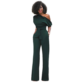Elegant woman wearing a black one-shoulder belted jumpsuit suitable for formal evening wear, showcasing her black hair and posing with her hand on her waist.