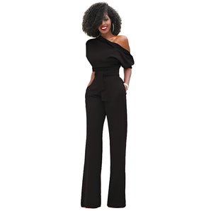 A woman wearing a black one-shoulder belted jumpsuit showcasing elegant formal evening wear, designed with a fitted waist and wide legs.