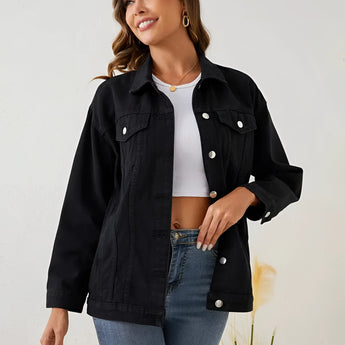 Woman wearing a black oversized denim jacket with cropped streetwear fashion, smiling with visible hair and shoulders, showcasing the jacket's sleeves and waist.