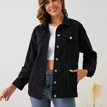 Woman smiling and standing in a black oversized cropped denim jacket with sleeves rolled up and a casual streetwear fashion style.