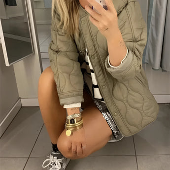 Black oversized quilted jacket for women, featuring a lightweight urban puffer style with a focus on fashion-forward outerwear. The jacket highlights a jointed design with distinct arm and shoulder details, a sleek neck, and long sleeves. The waist is subtly accentuated, contributing to the overall chic and modern look.