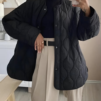 Black oversized quilted jacket for women, showcasing lightweight design and urban style. The puffer jacket features a quilted pattern, long sleeves, and a high collar, emphasizing the shoulders and neck area.