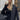 Women's black oversized quilted jacket with long sleeves, featuring a lightweight urban puffer design; model standing with a casual gesture showcasing the jacket's fashionable outerwear style.