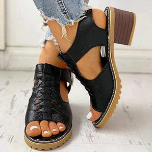 Black woven leather peep toe chunky heel clogs worn by a person, showcasing the footwear's stylish design and craftsmanship.