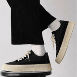 Black platform fashion sneakers with a textured sole, shown ankle-height on a person's foot.