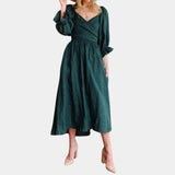 
A woman wearing an elegant emerald green puff sleeve midi dress, featuring a tie waist design, suitable for casual and spring occasions.