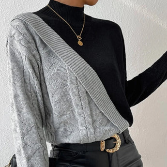 Black ribbed knit turtleneck sweater featuring chunky contrast sleeves, with a blend of black, white, and grey colors.