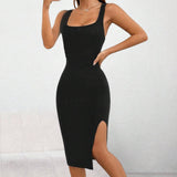 A woman wearing a black ribbed midi dress with a square neckline and side slit, form-fitting in style, posing with hands on hips.