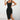 A woman wearing a black ribbed midi dress with a square neckline and side slit, form-fitting in style, posing with hands on hips.