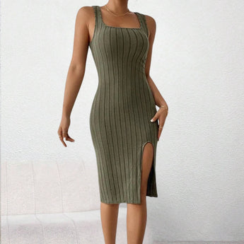 
A woman wearing a form-fitting green ribbed midi dress with a square neck and side slit, emphasizing the shoulders and arms.