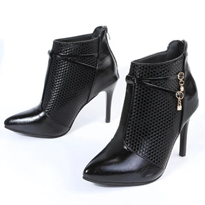 Black shiny leather high heel ankle boots with a snake pattern and chain detailing, showcasing a stylish and modern fashion design.
