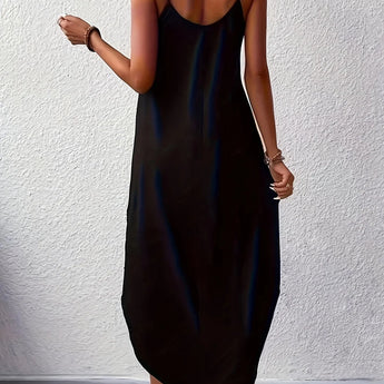 A woman standing and wearing a black sleeveless maxi dress with side pockets, showcasing a casual ankle-length fit.