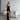 Black slit evening gown in slim fit, sleeveless design, worn by a model. The dress is a maxi length that elegantly highlights the shoulders and legs, perfect for formal events.