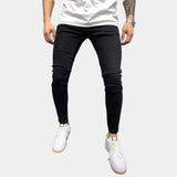 Black stretch skinny jeans for men in a trendy urban style, size 3XL, showcasing a slim fit design on a male model. The focus is on the jeans, highlighting their fit and style, along with some visible parts of the human body such as the legs and knees.