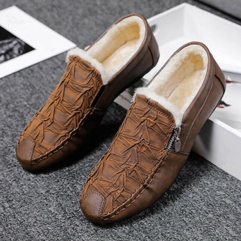 Black textured leather slip-on loafers with zipper for men displayed on a wooden surface, showcasing their sleek design and fashionable appearance.