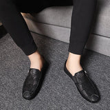 Black textured leather slip-on loafers with a zipper for men, displayed on a solid background.