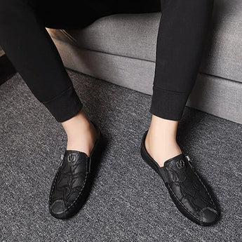 Black textured leather slip-on loafers with a zipper for men, displayed on a solid background.
